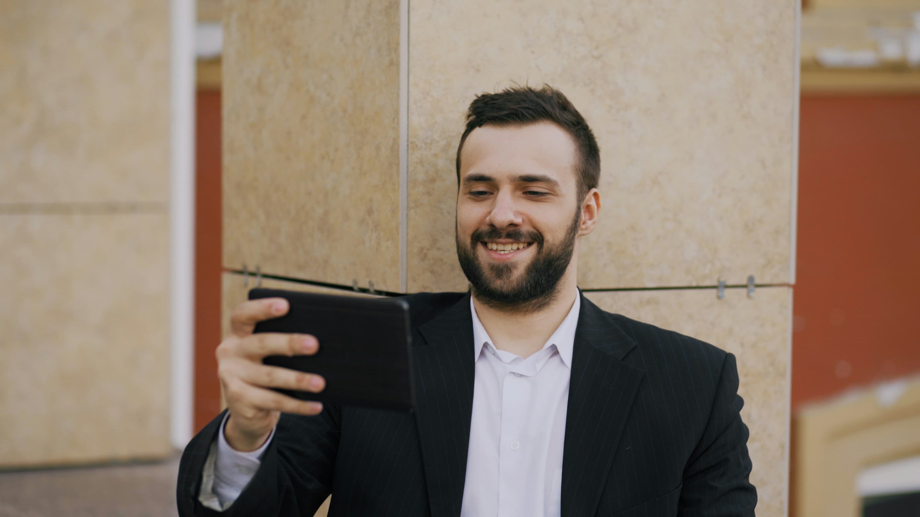 Man in suit smiling while looking at tablet