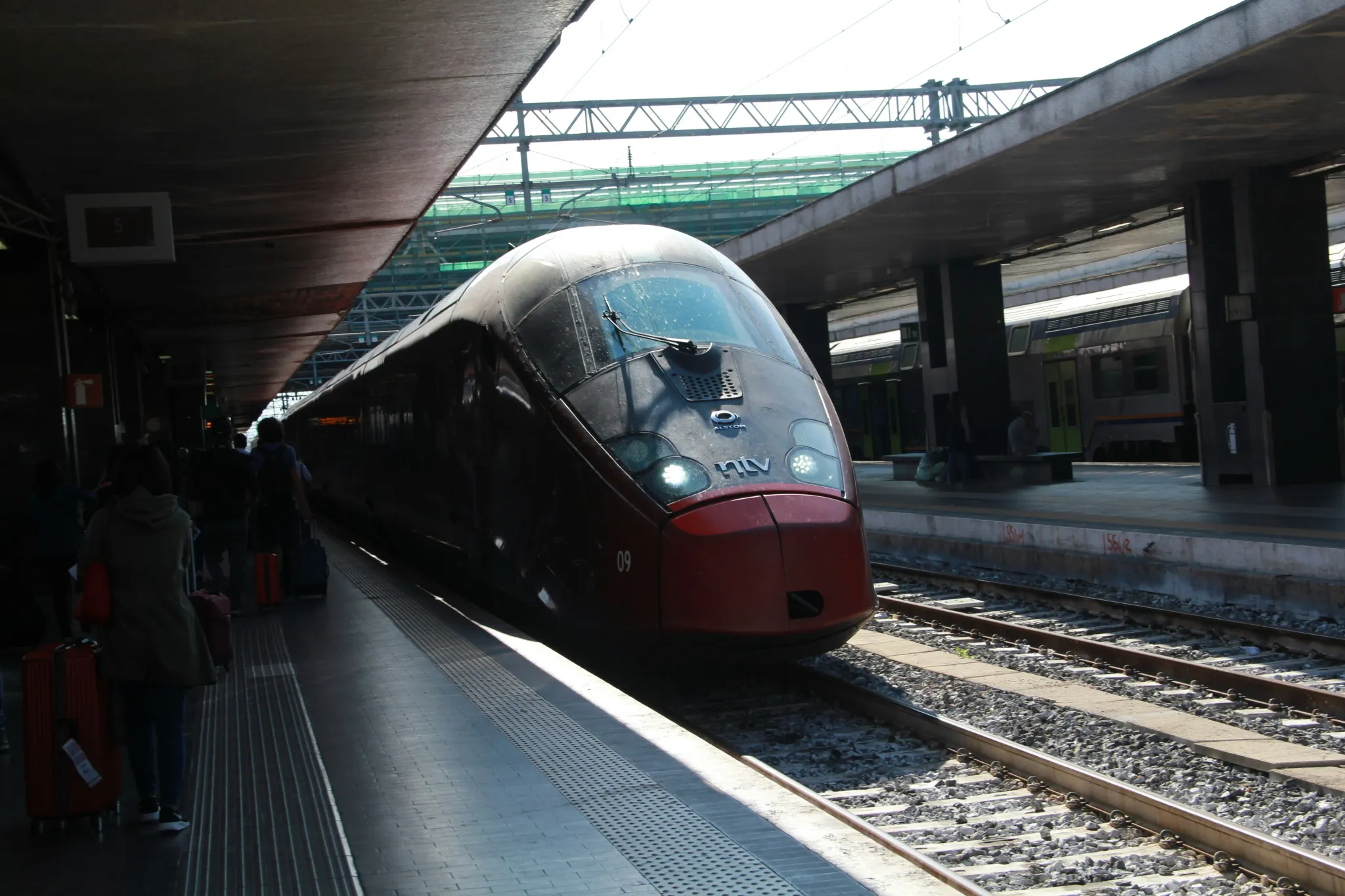 A sleek red train at a station platform.