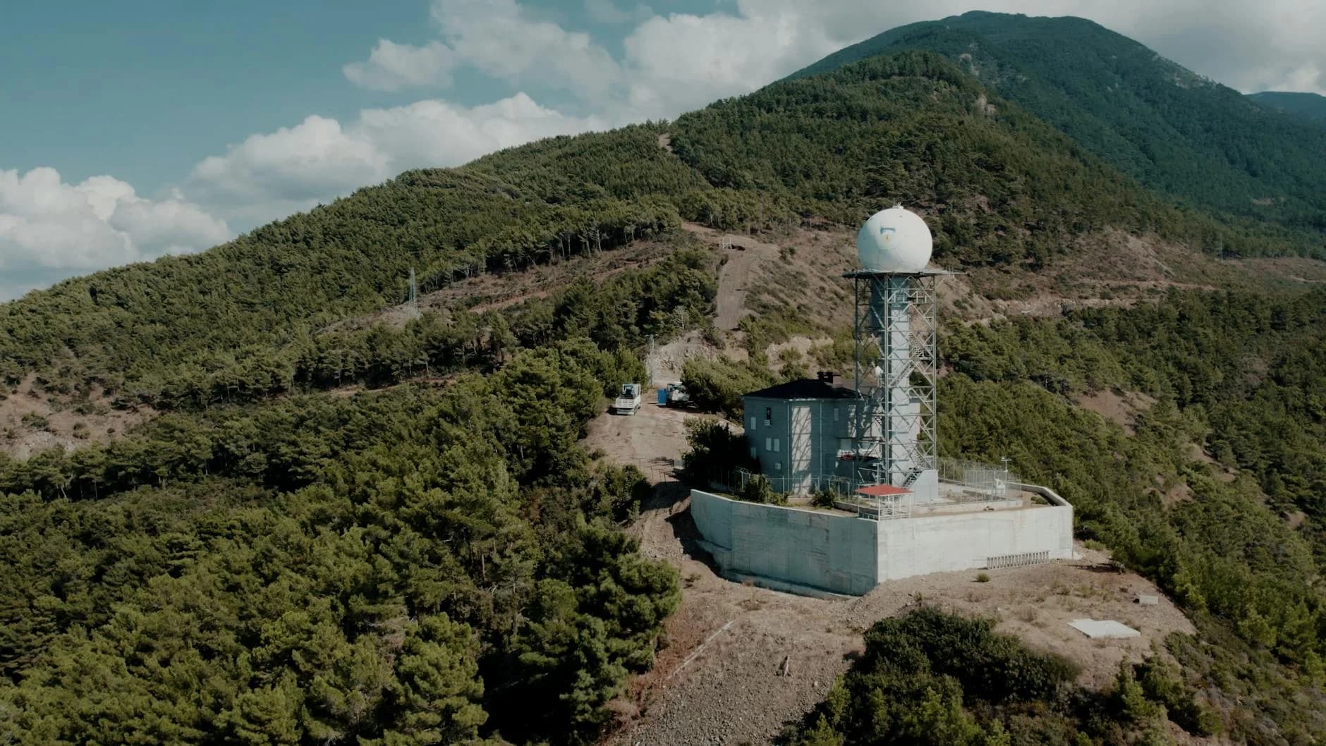 Weather station nestled in the lush mountains of Hatay, Türkiye, under a clear sky.