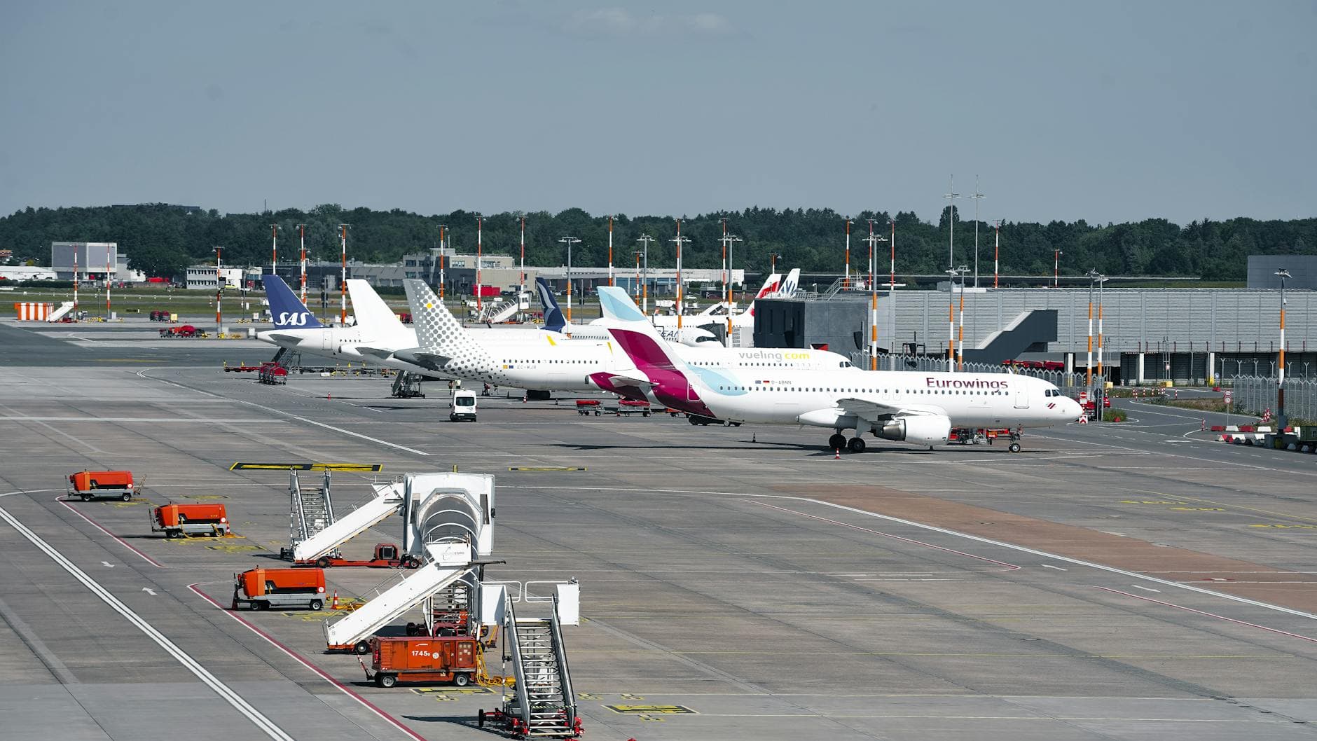 A busy scene at Hamburg Airport with various planes parked at the terminal during the day.