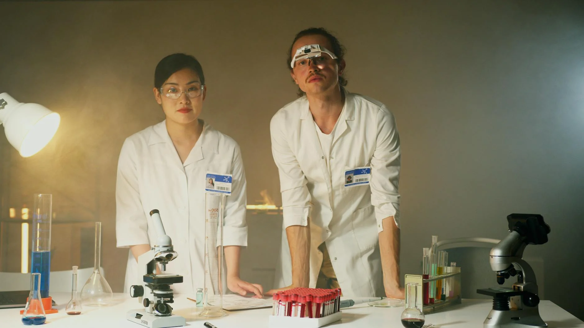 Two scientists conducting experiments in a lab, using microscopes and equipment.