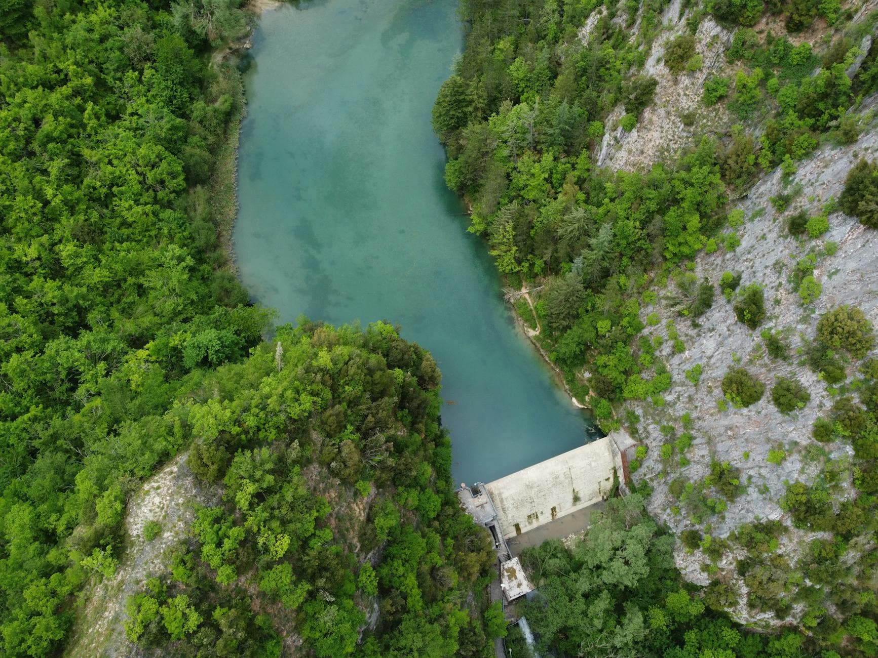 Aerial shot of a dam and river surrounded by lush greenery in Umbria, Italy.