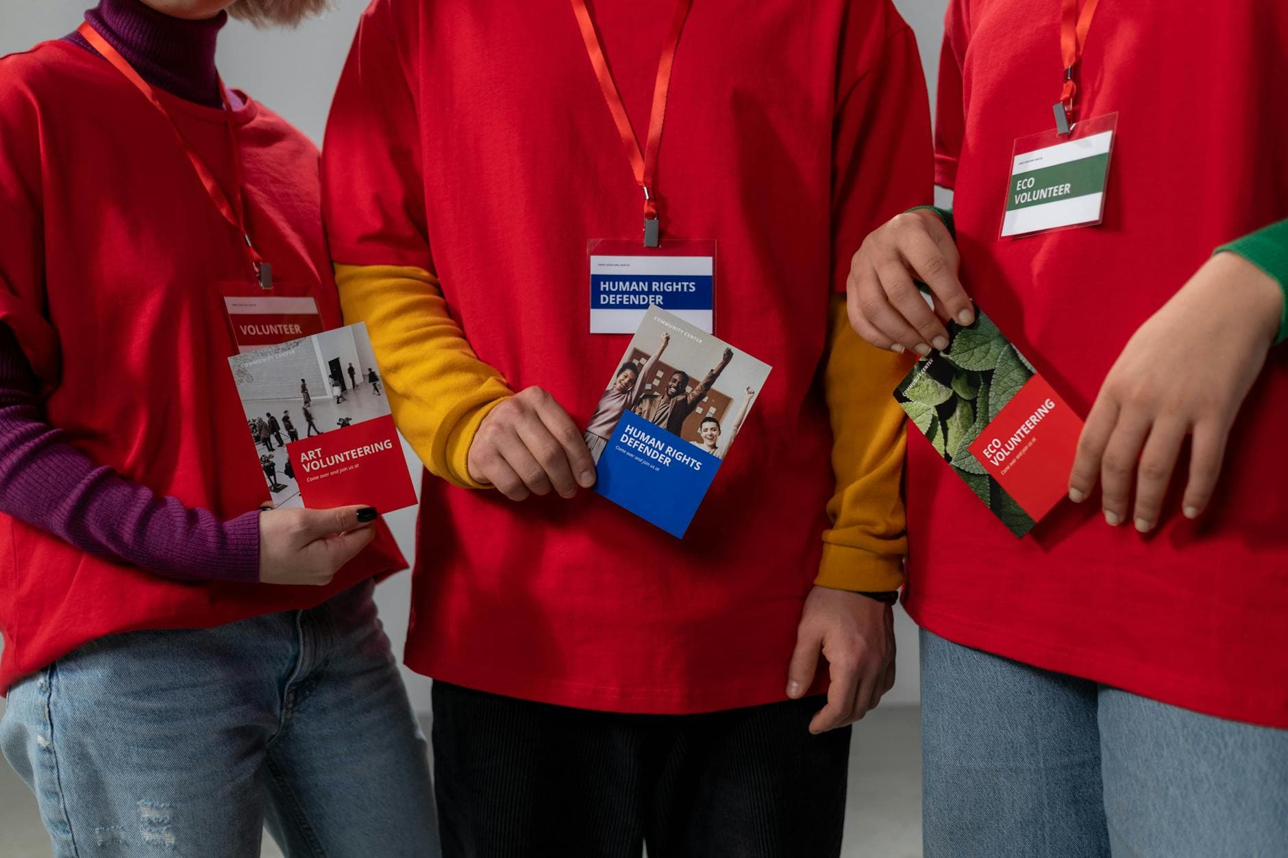 Volunteers in red shirts holding informational booklets on art and eco volunteering.