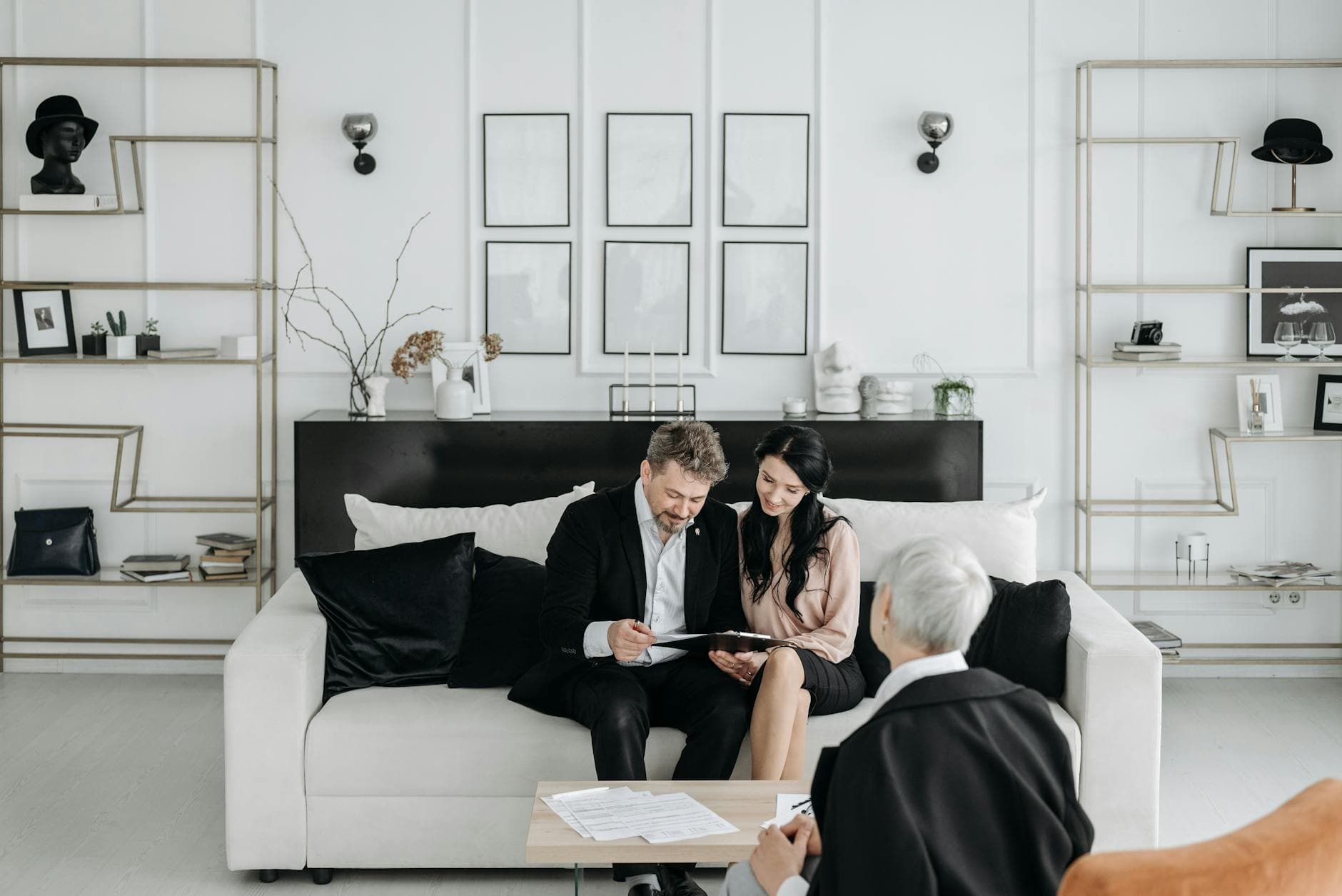 Couple consulting with a social worker in a modern living room setting, discussing documents.
