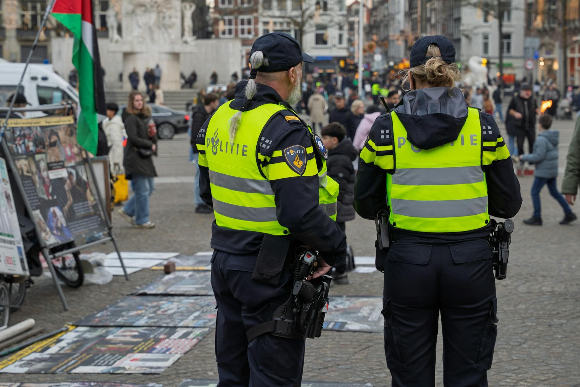 Two Dutch police officers monitor a busy square in Amsterdam, ensuring public safety.