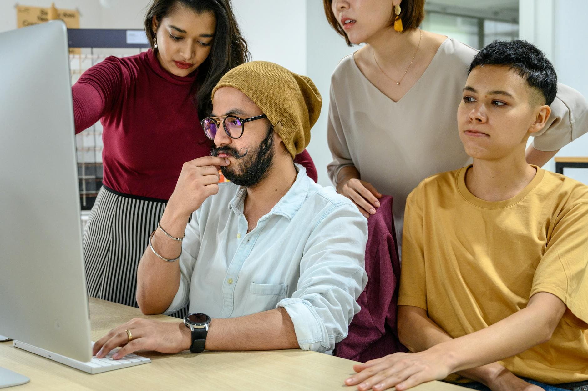 Diverse colleagues collaborating at a computer in a modern office setting.