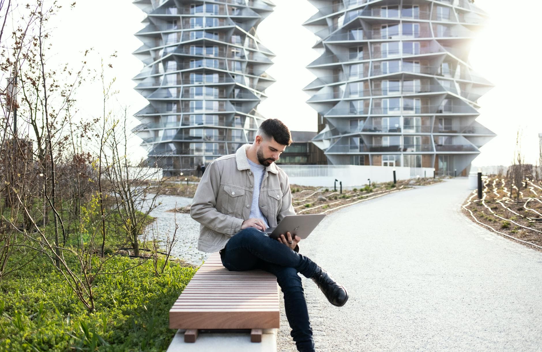 Urban scene of a man working on a laptop in a modern Copenhagen park.