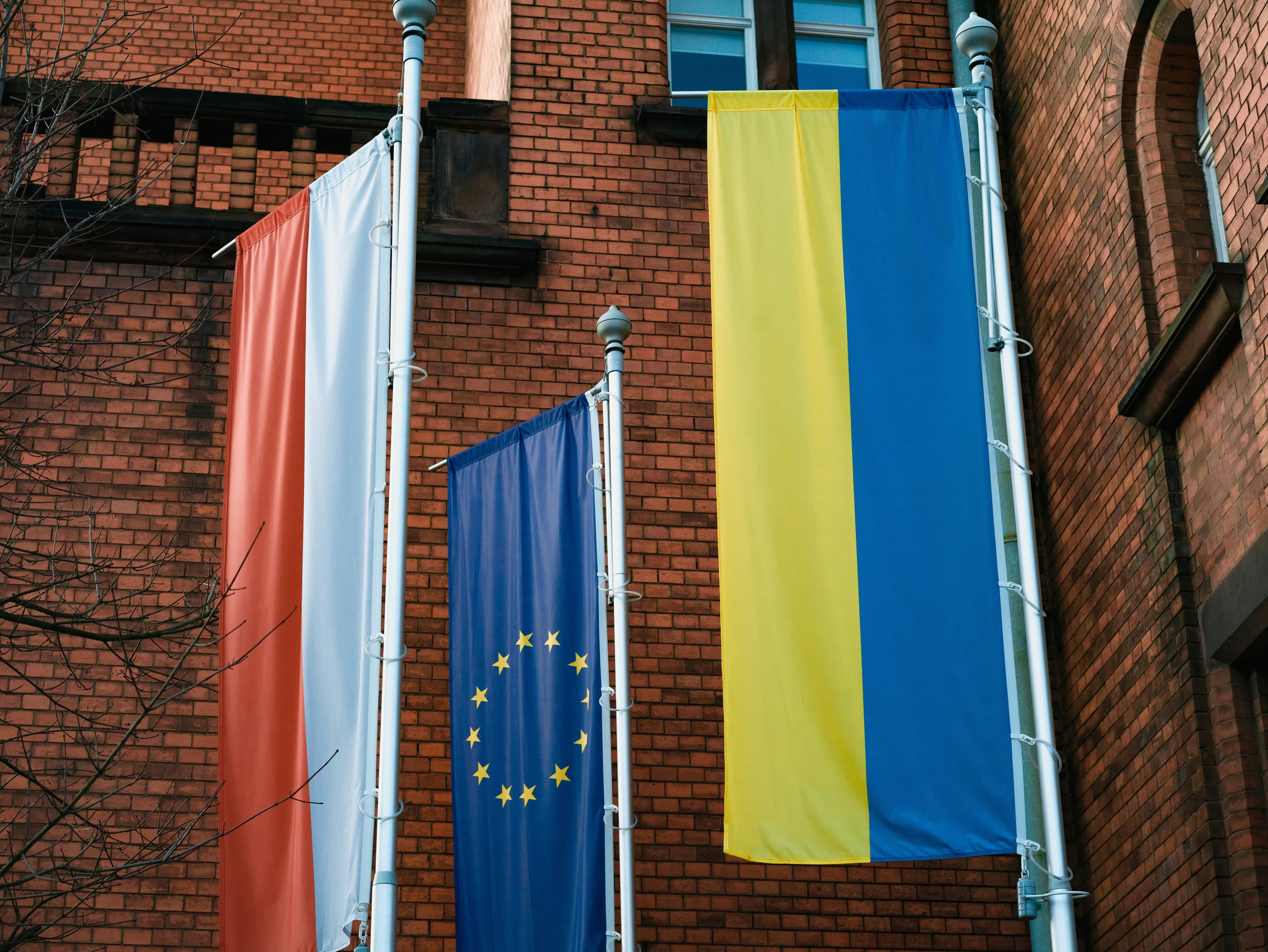 a brick building with three flags hanging from it's sides