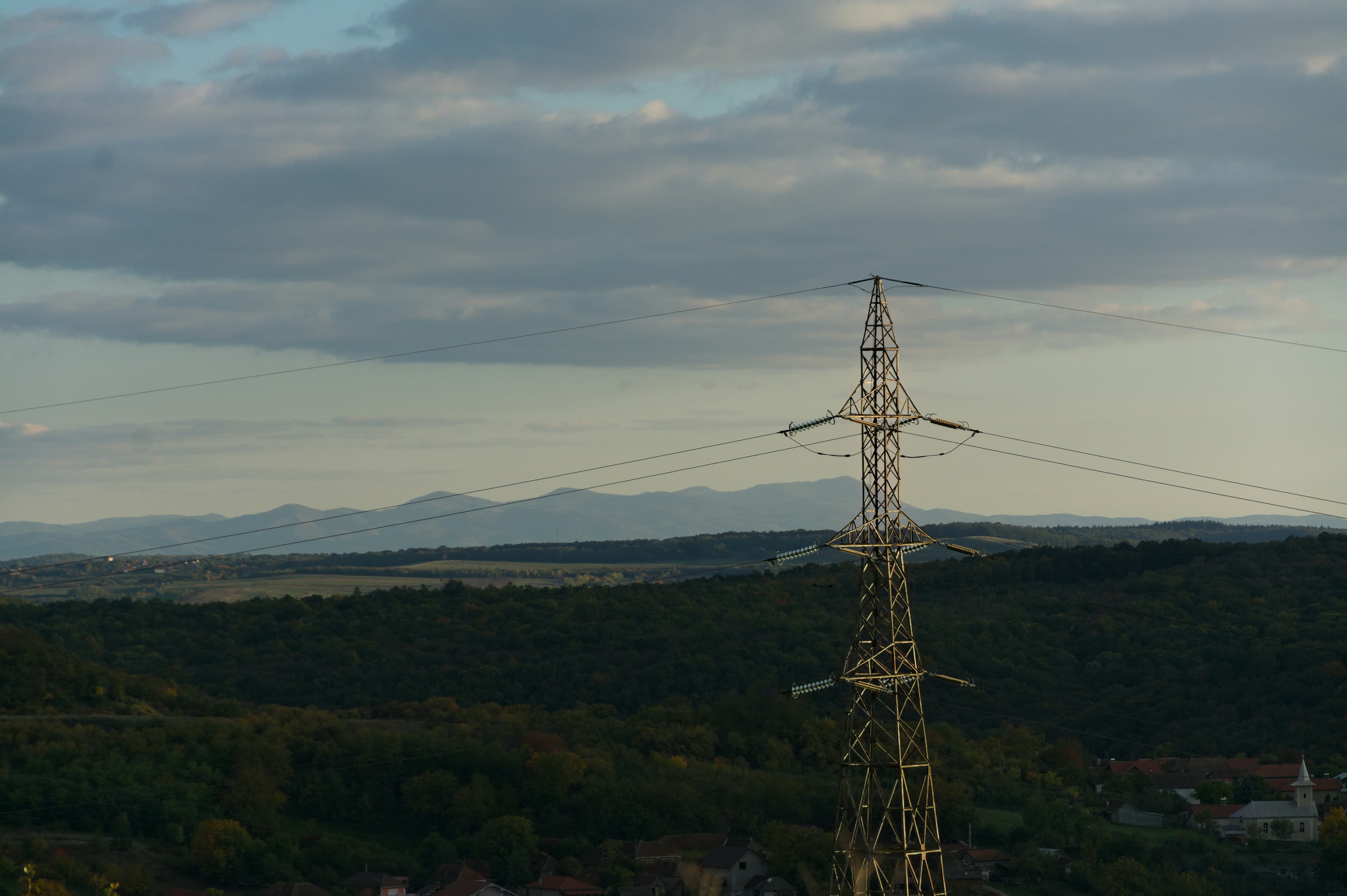 Electricity pylon against a cloudy sky over hills