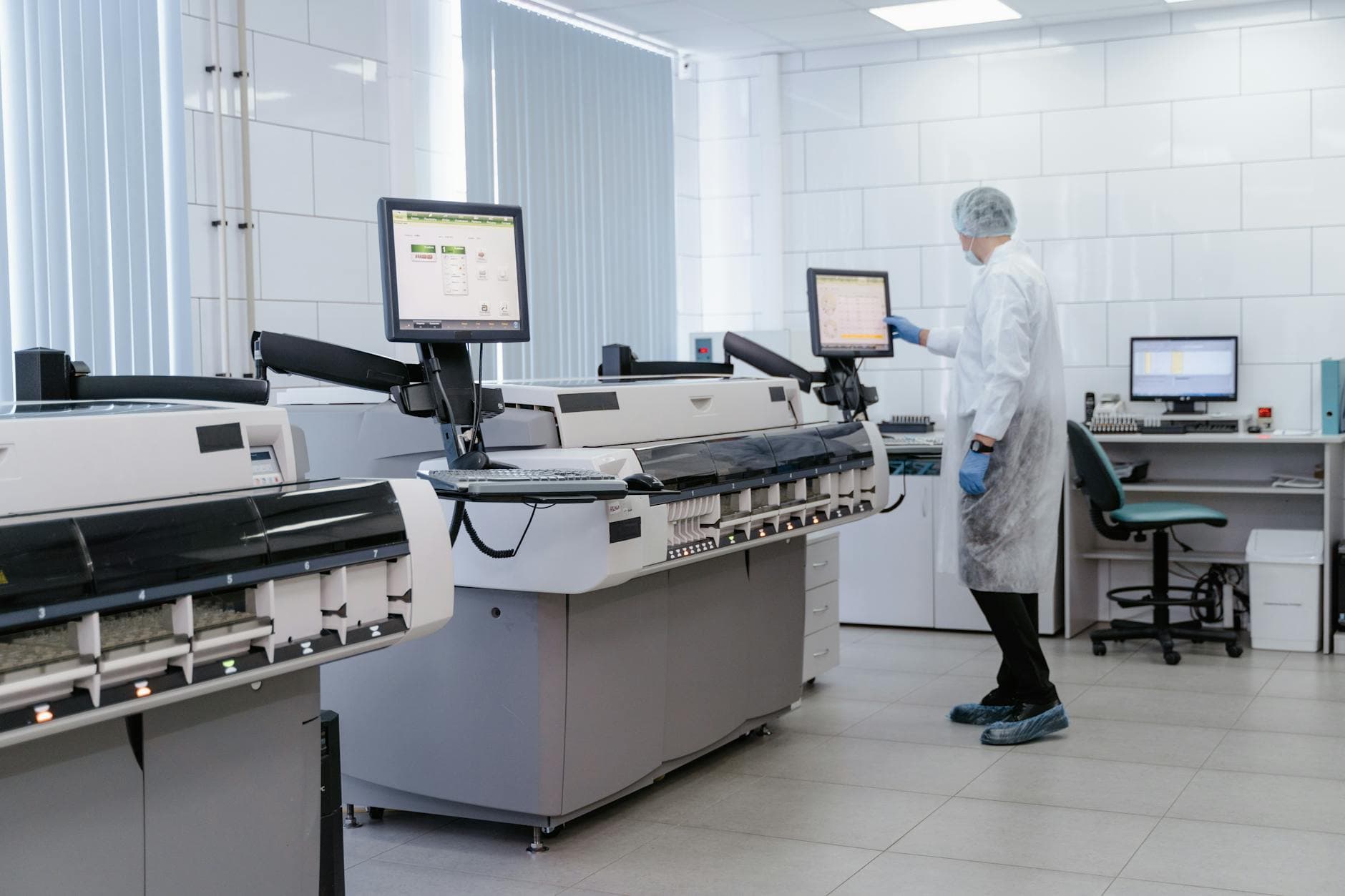 Scientist in a lab gown interacting with equipment in a modern laboratory setting.