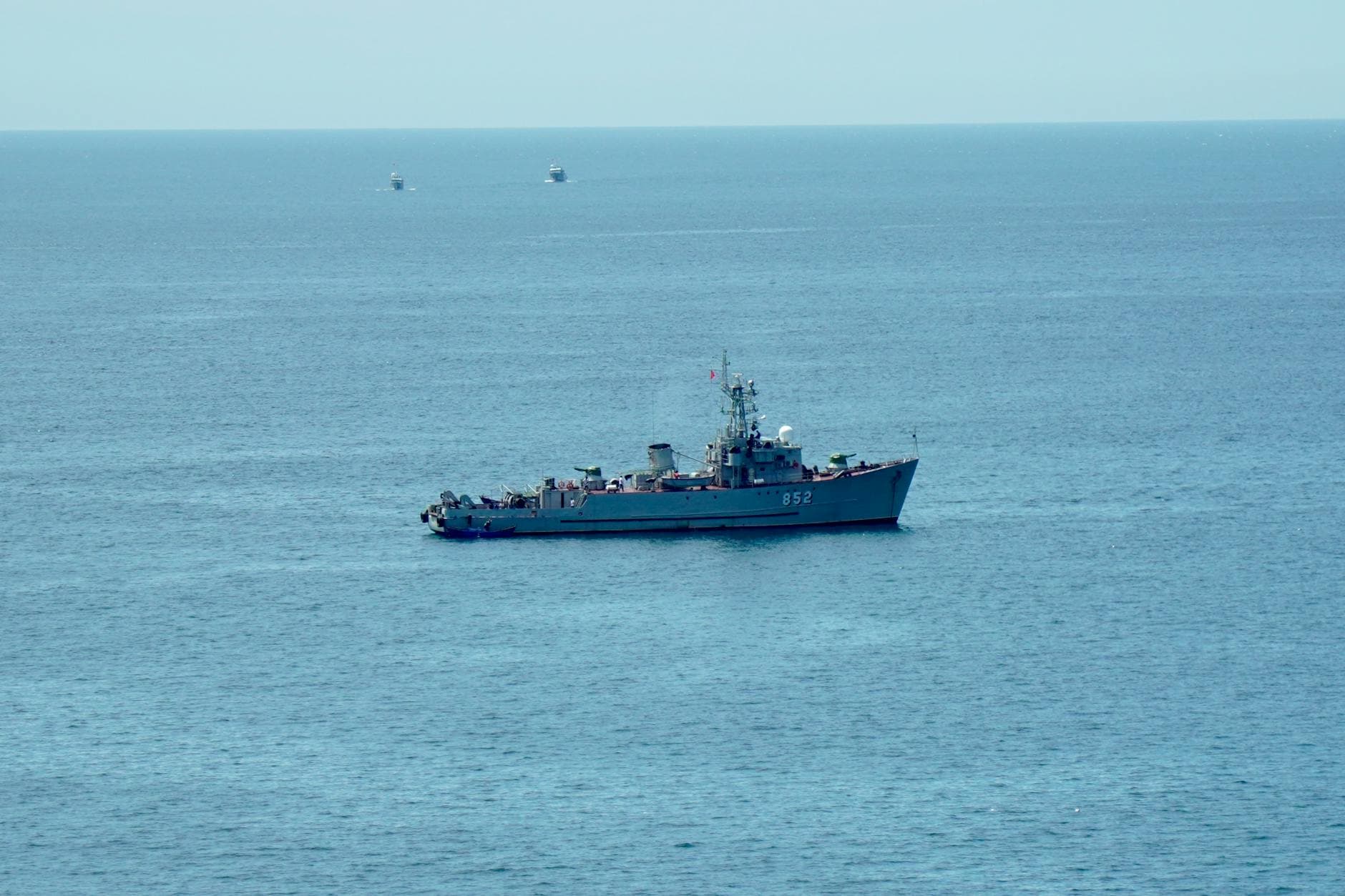 A military ship navigating the calm blue ocean under a clear sky, showcasing nautical power.