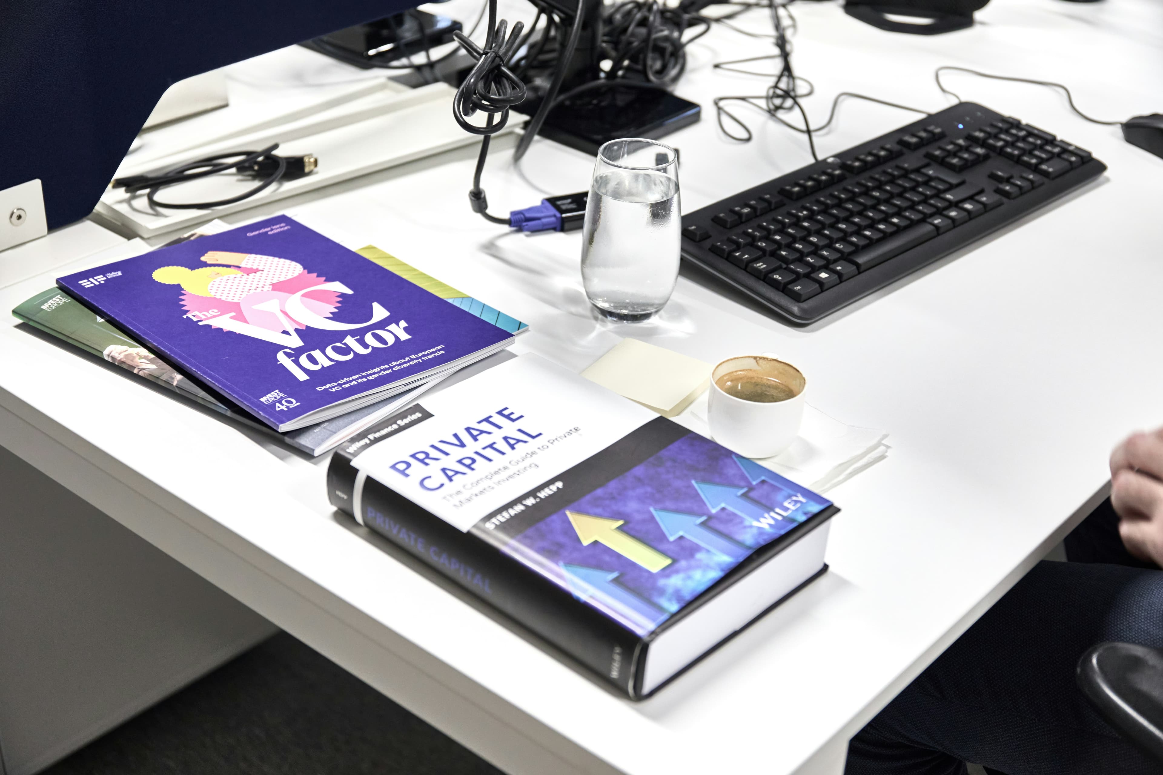 Desk with books, keyboard, and coffee cup of coffee.