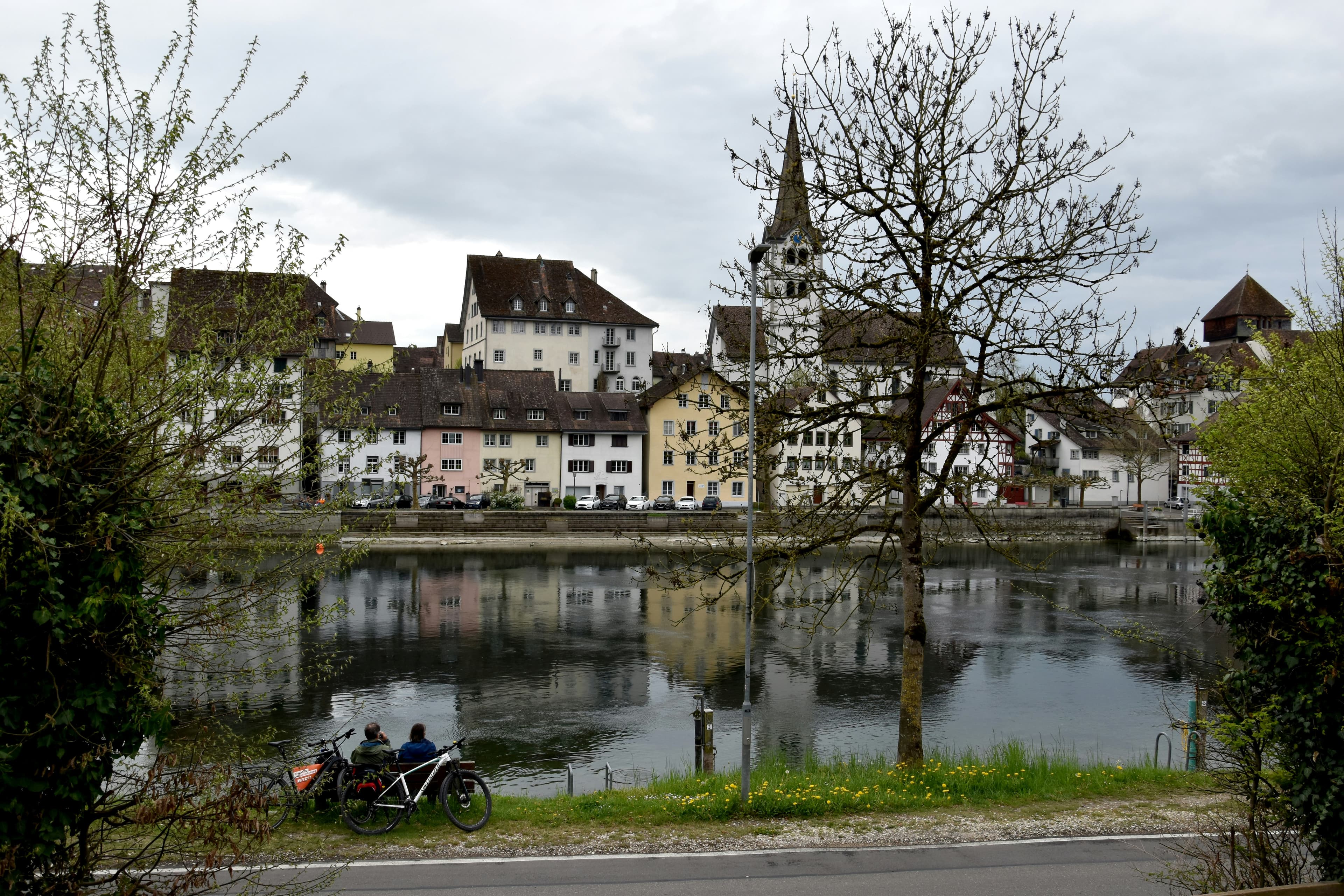 City buildings reflect in the calm water below.
